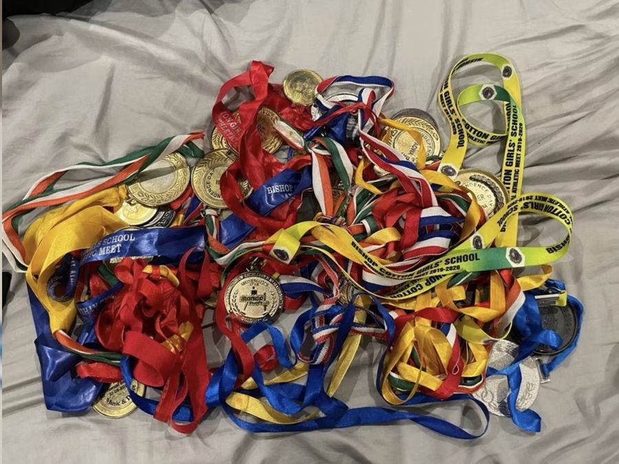 A pile of athletics medals and ribbons from school meets
